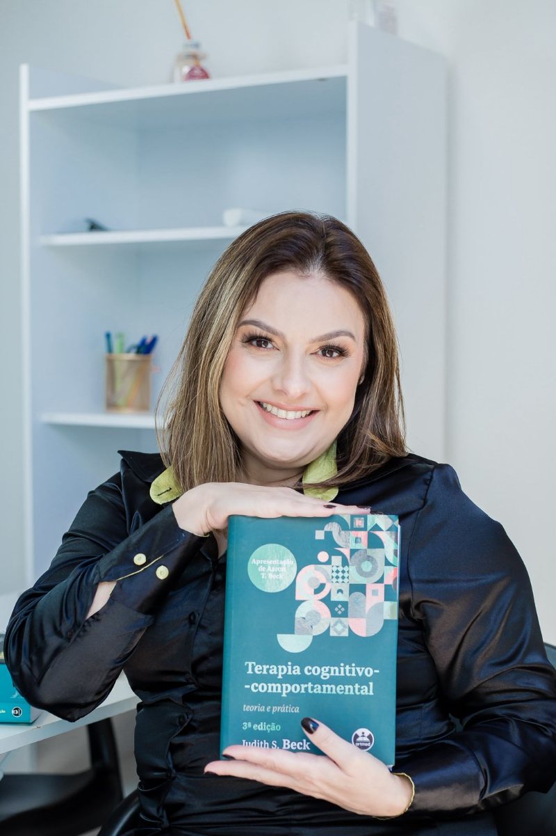 Michelle Curado segurando o livro Terapia Cognitivo-Comportamental, de Judith S. Beck